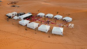 Travelers riding camels across the golden dunes of Merzouga Desert at sunset, capturing the essence of a Sahara adventure in Morocco